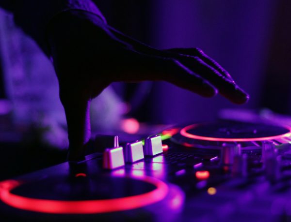 selective focus silhouette photography of man playing red-lighted DJ terminal